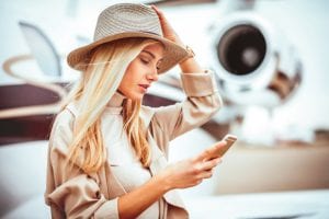 woman with hat looks at Jet Linx Mobile App on phone