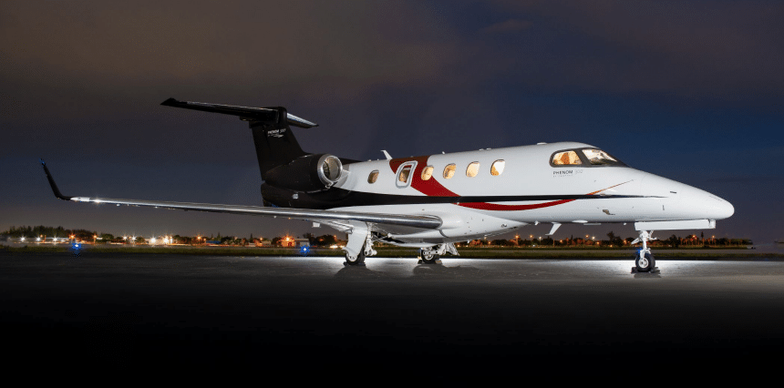 Phenom 300 light jet private aircraft on a runway at night.